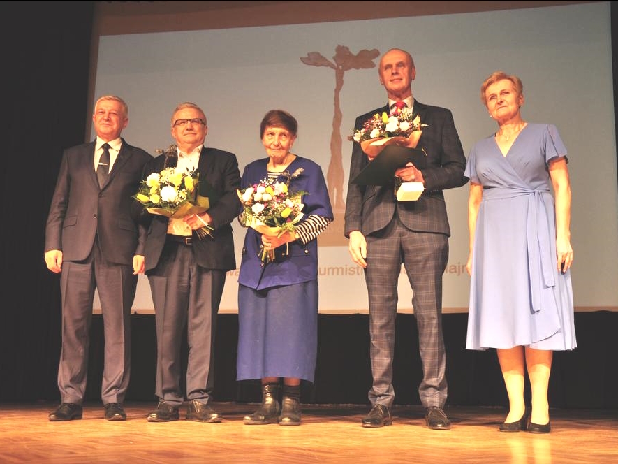na scenie stoją dwie kobiety i trzech meżczyzn. Laureaci trzymaja w dłoniach kwiaty i statuetki Querkus