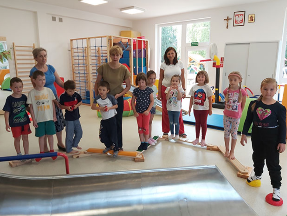 Dzieci i opiekunowie w sali gimnastycznej