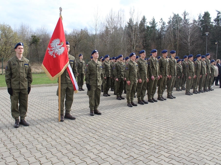 Uczniowie Oddziału Przygotowania Wojskowego stoją w szeregu ze sztandarem