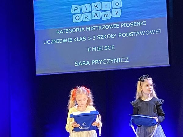 Dziewczynki stoją na scenie i trzymają torby z nagrodami