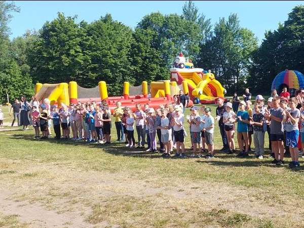 uczestnicy pikniku rodzinnego. W tle widać dmuchany plac zabaw