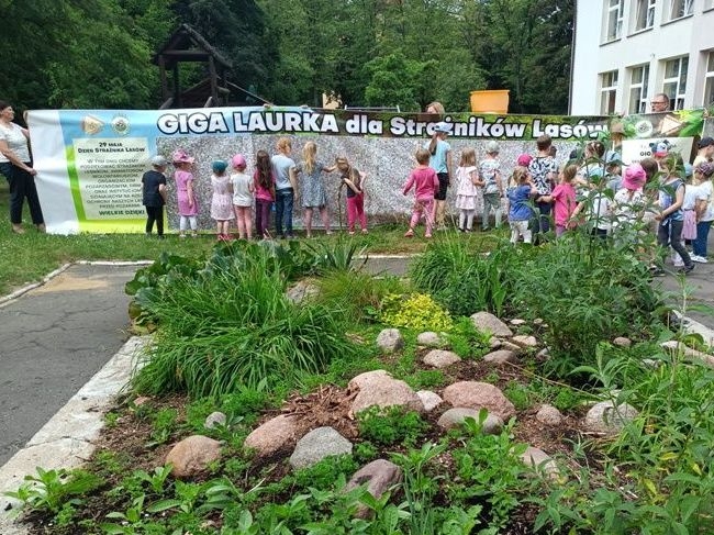dzieci stoją przy ogromnej laurce