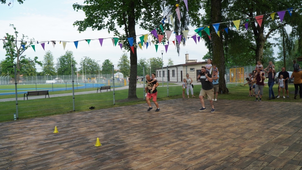 Dzieci i ich ojcowie podczas zabaw ruchowych na świeżym powietrzu.