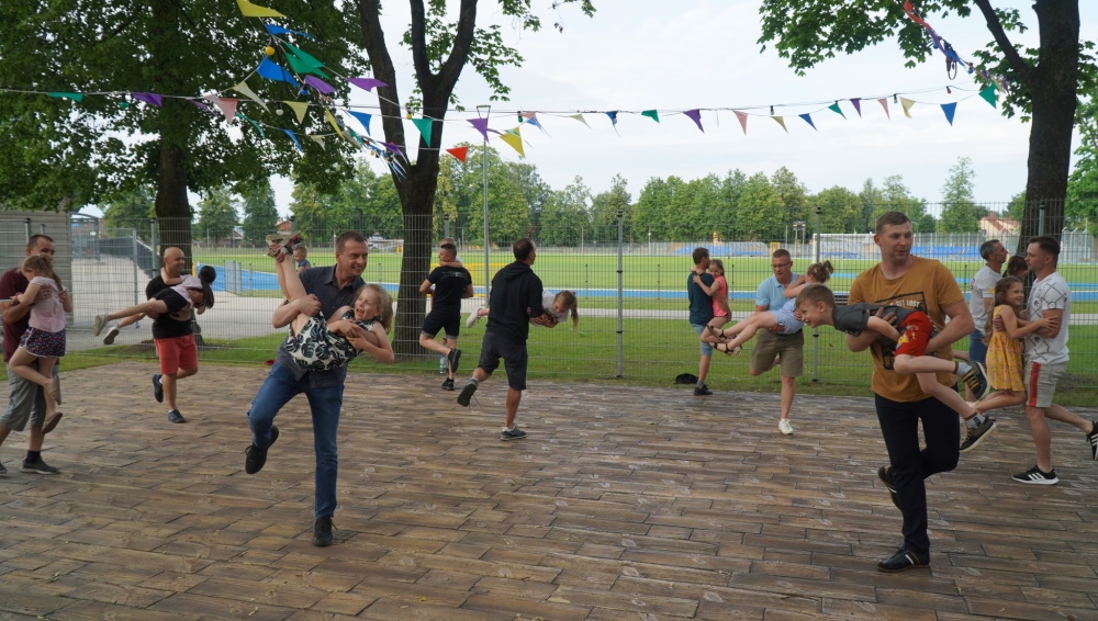 Ojcowie trzymają swoje dzieci na rękach.