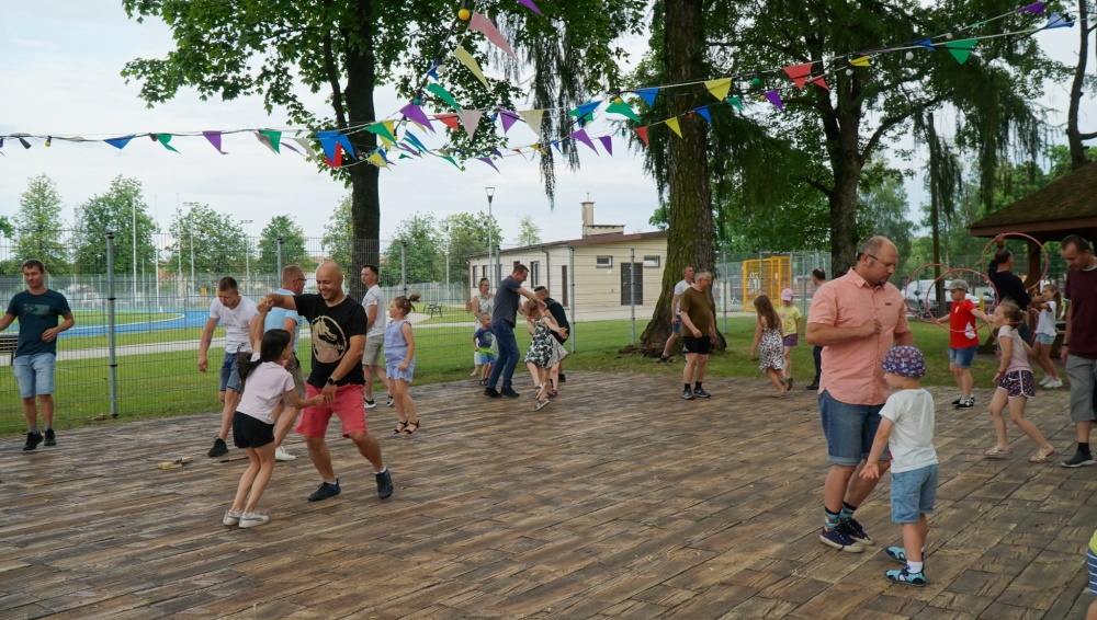 Dzieci i ich ojcowie podczas zabaw ruchowych na świeżym powietrzu.