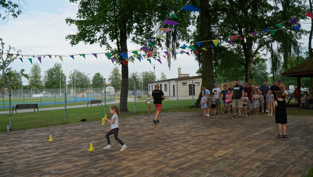 Dzieci i ich ojcowie podczas zabaw ruchowych na świeżym powietrzu.