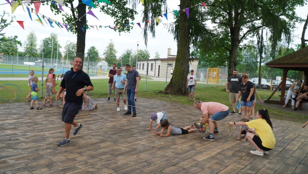 Dzieci i ich ojcowie podczas zabaw ruchowych na świeżym powietrzu.