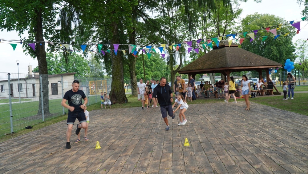 Dzieci i ich ojcowie podczas zabaw ruchowych na świeżym powietrzu.