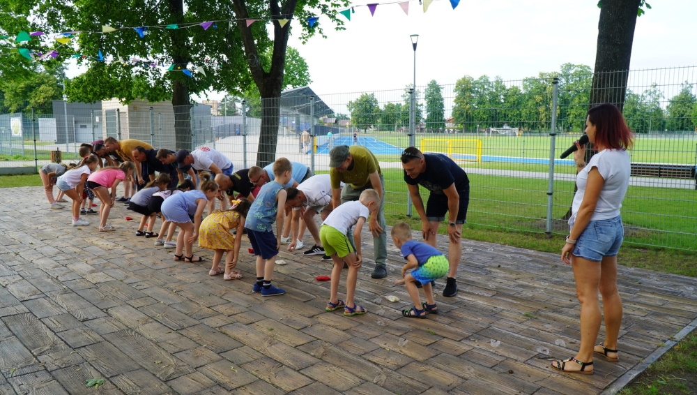 Dzieci i ich ojcowie stoją w dwóch rzędach na przeciwko siebie.