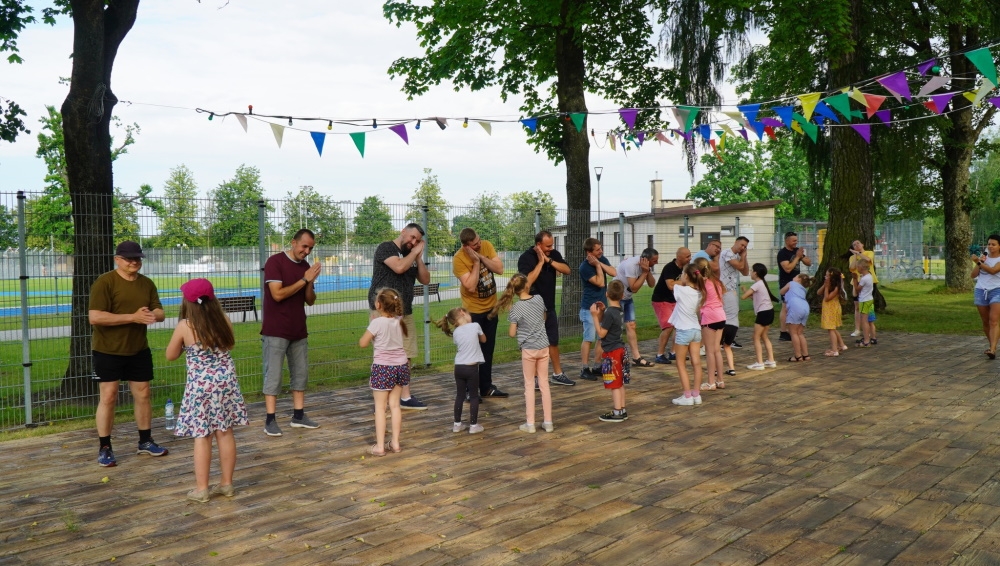 Dzieci i ich ojcowie stoją w dwóch rzędach na przeciwko siebie.