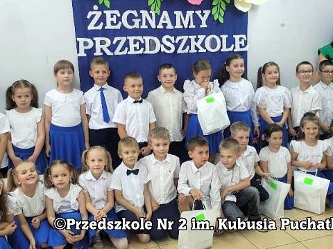 zdjęcie grupowe przedszkolaków wraz z opiekunami na tle niebieskiego baneru z napisem Żegnamy przedszkole