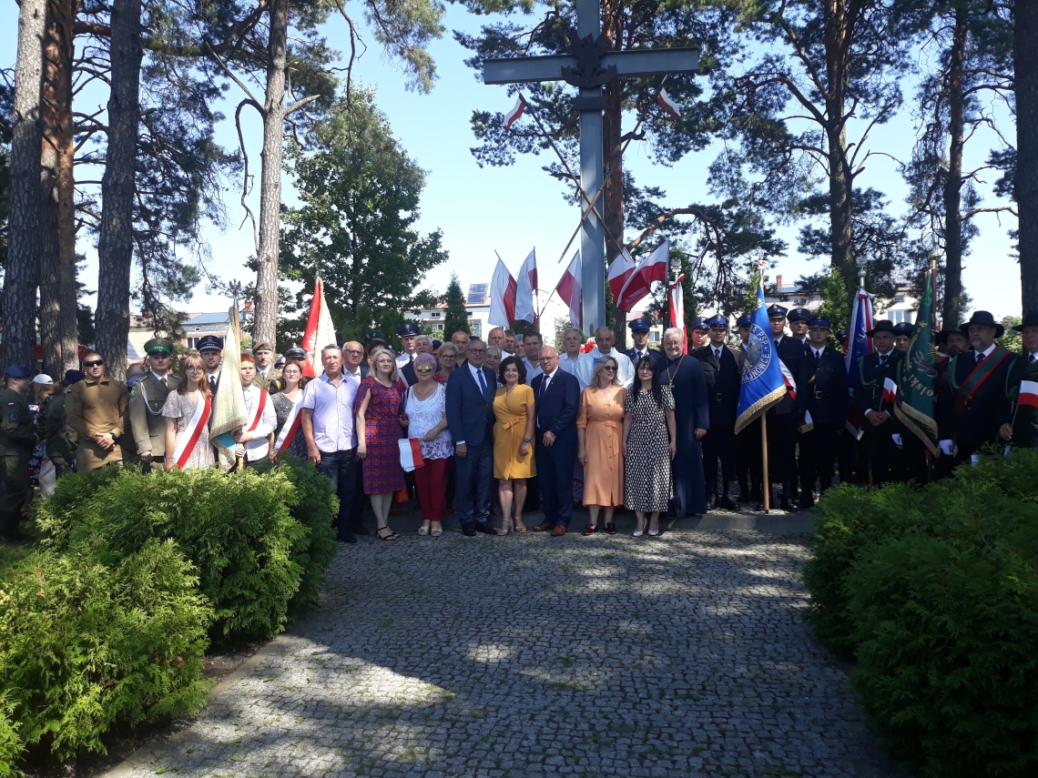 zdjecie grupowe gości przybyłych na uroczystosci na tle pomnika