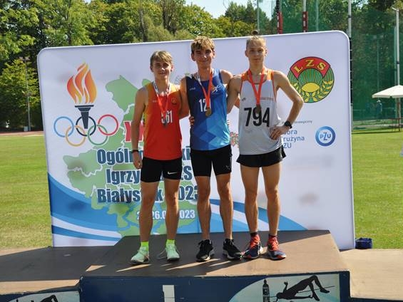 trójka zawodników stoi na podium