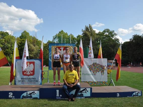 dziewczęt stoją na podium, trener siedzie niżej