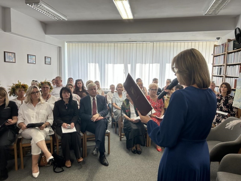 Zdjęcie widowni. Dyrektor biblioteki trzyma rozłożoną teczkę.
