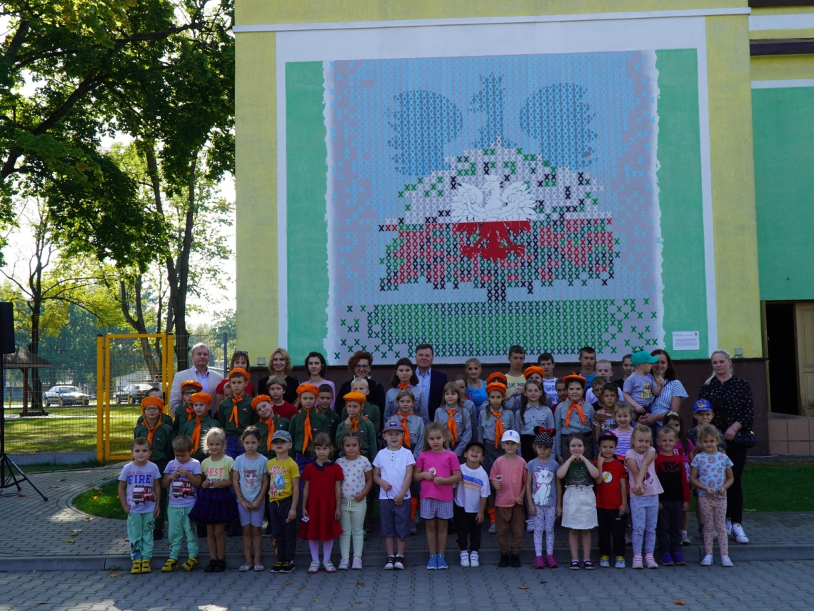 zdjecie grupowe gości przybyłych na otwarcie na tle muralu