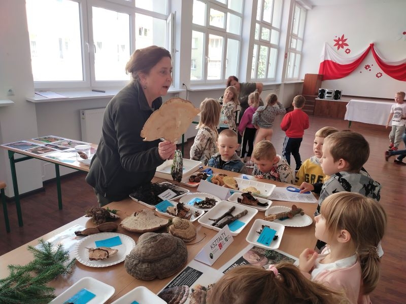 kobieta pokazuje dzieciom eksponat grzyba