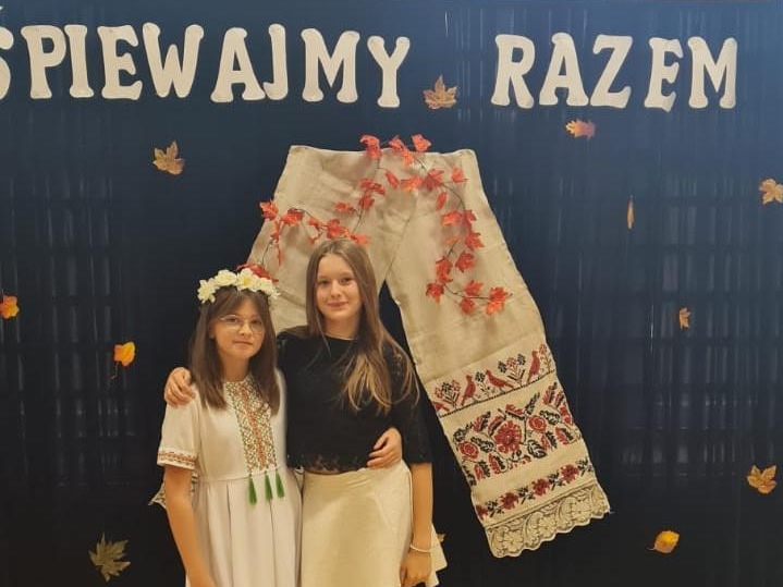 Dwie dziewczynki. W tle widać scenografię z napisem ŚPIEWAMY PANU
