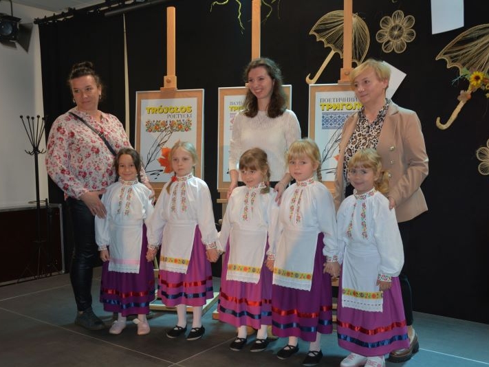 Dziewczynki ubrane w białoruskie stroje. Z tyłu stoją opiekunki