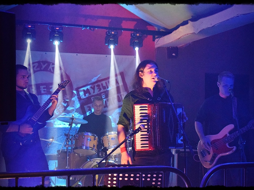 zespół na scenie. W tle widać baner z napisem MUZYKA BEZ ZASTRZEŻEŃ