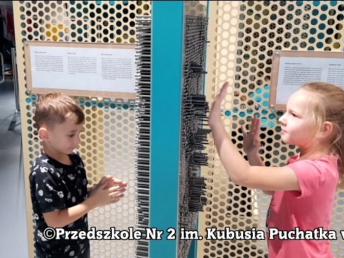 chłopiec i dziewczynka naciskaja na wystające ze ścianki pręty