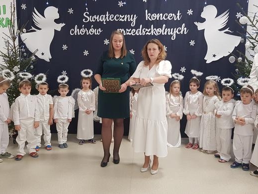 W scenerii światecznej soją dzieci ubrane na biało oraz 4 opiekunki