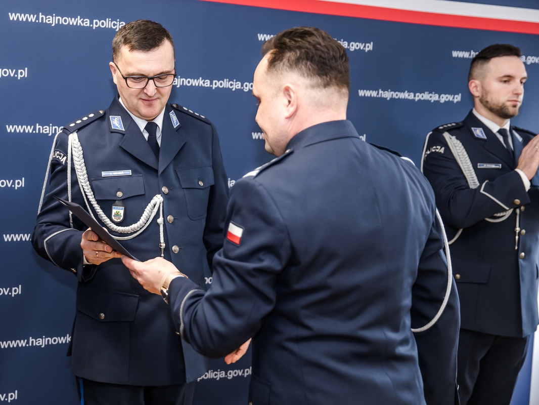 mężczyzna przekazuje drugiemu mężczyźnie dokumenty. Obaj są w mundurach
