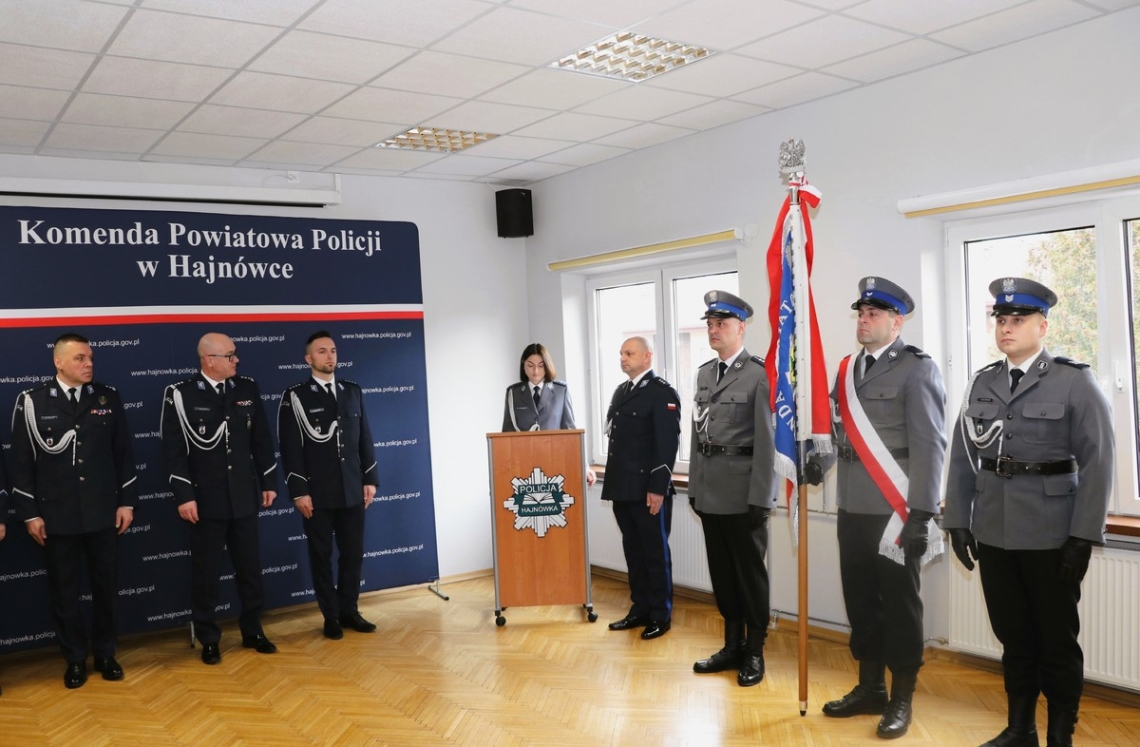 przymównicy stoi kobieta, z prawej strony poczet sztandarowy, z lewej mężczyźni w mundurach