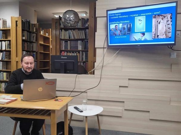 mężczyzna siedzi przy laptopie i wyświetla prezentację na rzutniku