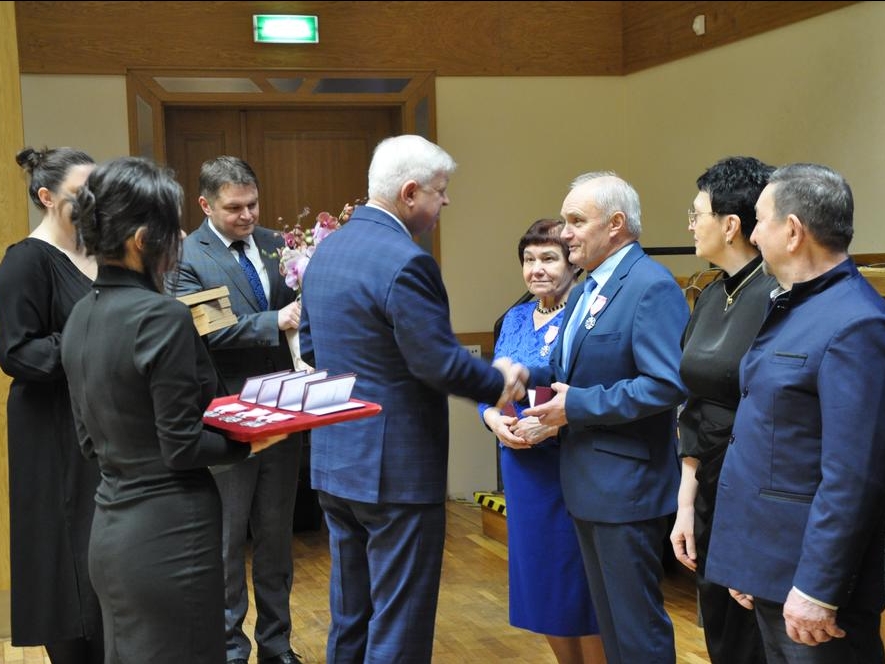 Burmistrz podaje rękę jubilatom. Obok stoi Zastępca publistrza z kiwatami i Zastępca Kierownika USC z medalami 