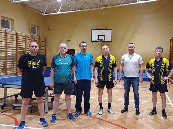 meżczyźni stoją przy stole do tenisa