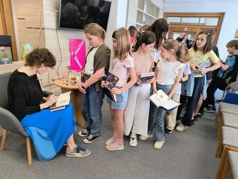 kobieta składa dzieciom autografy
