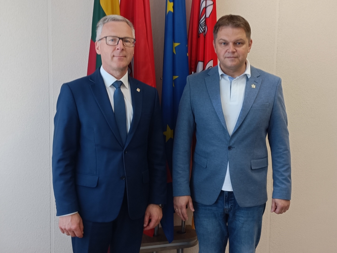 wspólne zdjęcie burmistrza i mera na tle flag