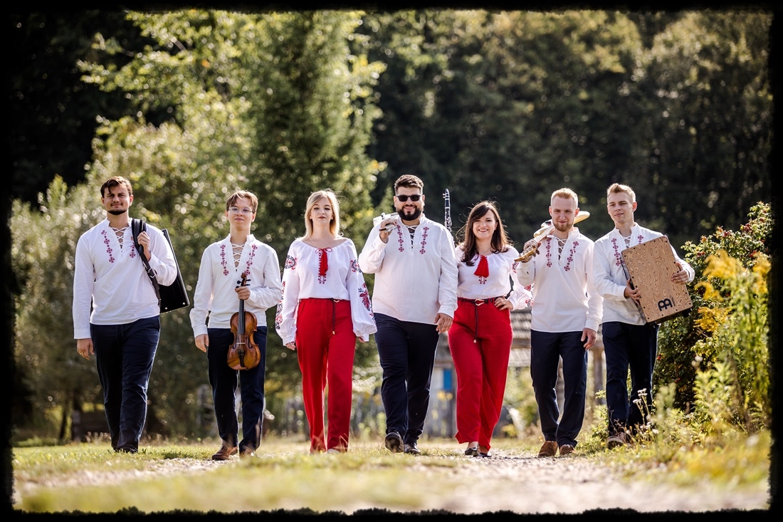 zdjęcie zespołu na polnej drodze. W tle widać las