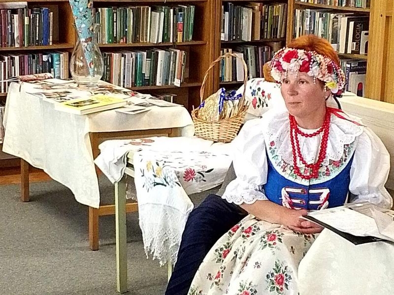 kobieta ubrana w ludowy stórj siedzi w czytelni miejskiej