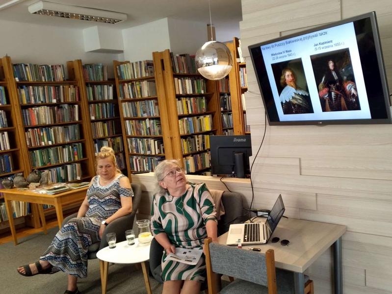 dwie kobiety siedzą w czytelni miejskiej i prezentują slajdy