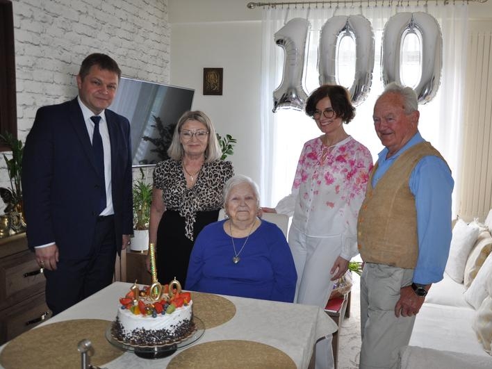 Jubilatka, jej córka i syn oraz burmistrz i pani kierownik USC pozują do zdjęcia. W tle widać balony z cyfrą 100