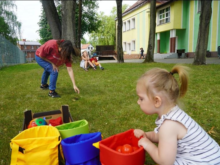 dziecko siedzi przy kolorowych torbach z piłeczkami