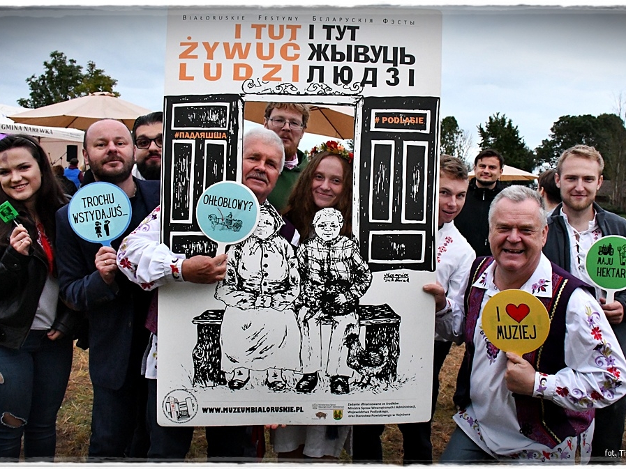 grupa ludzi pozuje do zdjęcia przy "ściance z napisem: I TAM ŻYWUĆ LUDZI"