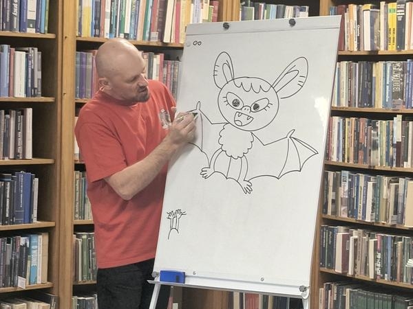 mężczyzna rysuje na planszy nietoperza