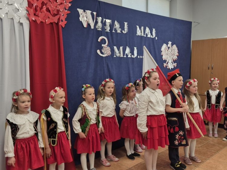  Dzieci w biało-czerwonych strojach prezentują program artystyczny. Stołówka, gdzie odbywała się uroczystość została udekorowana flagami oraz symbolami narodowymi, tworząc wyjątkową atmosferę.