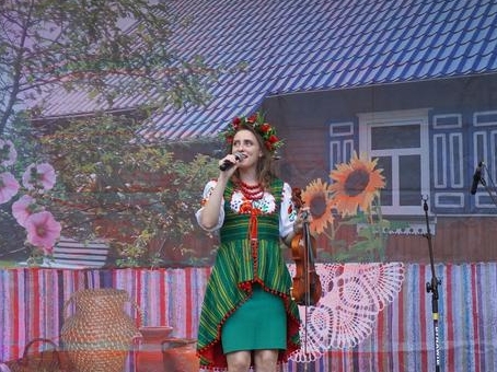 dziewczyna w stroju ludowym. W tle baer na którym widnieje drewniana chata
