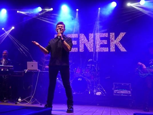 mężczyzna na scenie. W tle widać napis ZENEK