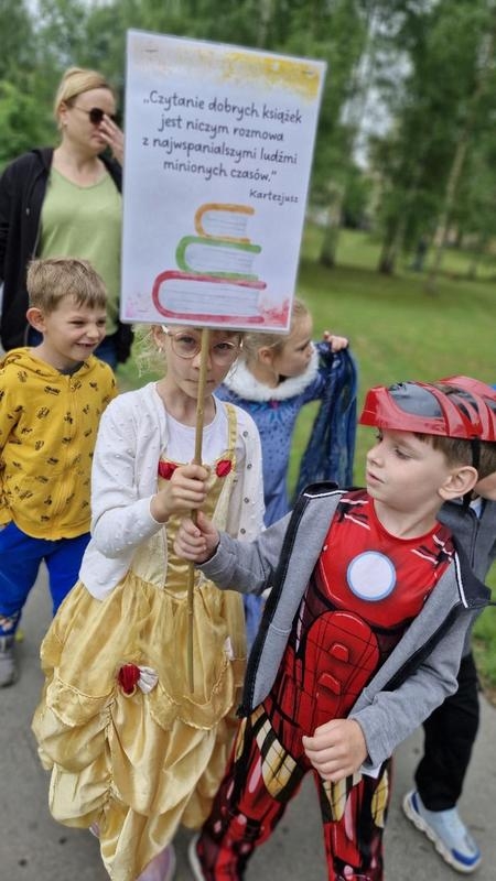 dzieci w bajkowych strojach trzymają transparent