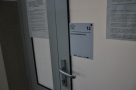 drzwi wejściowe do sali konferencyjnej, nad klamką umieszczona jest biała tabliczka z numerem i nazwą pomieszczenia, pod nimi wypukłe napisy w alfabecie Breailla
