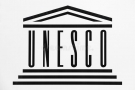 Logo przedstawia napis wielkimi literami: UNESCO. pod napisem znajdują się trzy poziome linie, a nad nim trójkąt w kształcie dachu.