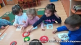 Dzieci siedzą przy stoliku, ozdabiaja pierniczki w kształcie misia.