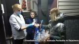 Na zdjęciu kobieta wręcza dwa kosze przewiązane niebieska wstążką kobiecie w białym kitlu i starszej pani.