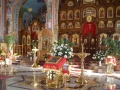wnętrze świątyni, na środku stoi anałoj z ikoną, po obu stronach obok niego stoją świeczniki oraz kwiaty; na wprost widoczny jest drewniany ikonostas w ikonami