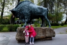 Dwie dziewczynki stojące na tle hajnowskiego Pomnika Żubra